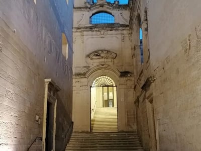Escalier menant à une belle porte ornée dans le centre historique de Lecce, illuminé par la lumière du soir.