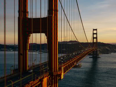 Pont du Golden Gate illuminé au crépuscule, surplombant la baie de San Francisco avec des voitures circulant.