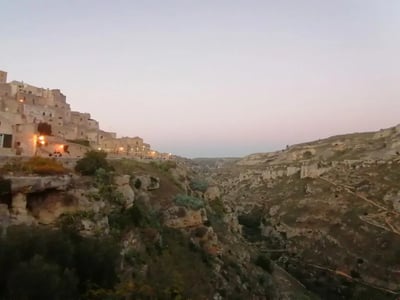 Vue panoramique du parc Murgia Materana au crépuscule, surplombant les formations rocheuses et l'architecture troglodyte.