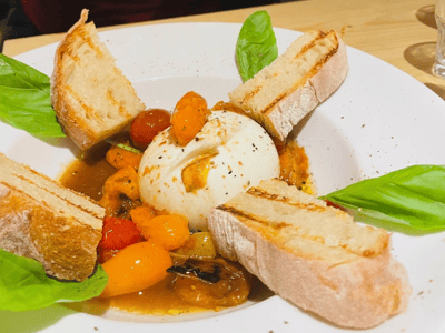 Burrata crémeuse accompagnée de tomates cerises et de pain grillé, servie au Gnam Pasta Factory.