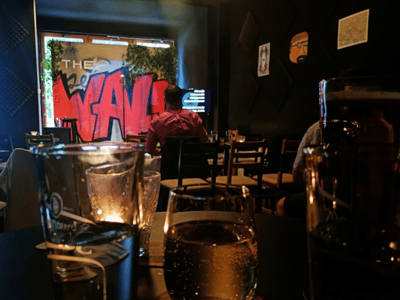 Vue intérieure de The Wall Comedy, avec des boissons sur la table et un décor artistique, créant une ambiance conviviale.
