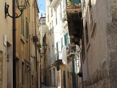 Picturesque alley of Altamura, with old facades and lampposts, evoking Mediterranean architecture.