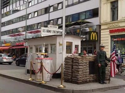 Checkpoint Charlie control post in Berlin, emblematic of the Cold War, with a soldier and American flags.