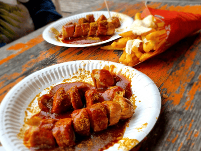 Mauerpark sausage served with crispy fries, perfect for a delicious outdoor snack break.