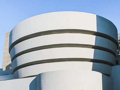 Iconic facade of the Guggenheim Museum in New York, with its distinctive circular shape and a blue sky in the background.