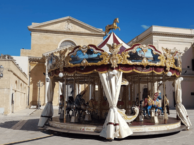 Colorful carousel set up in a square in Ugento, evoking childhood memories and family fun.