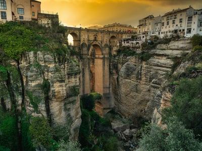 Le spectaculaire pont de Ronda surplombe les canyons dramatiques, illuminé par un ciel doré au crépuscule.