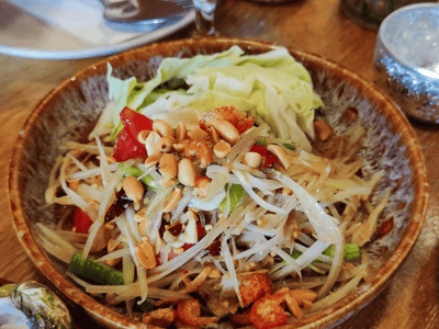 Salade de papaye verte garnie de cacahuètes et de légumes frais, spécialité culinaire de Larb Koi.