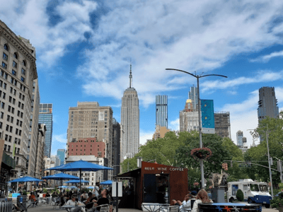 Animated view of the street in the Flatiron District, with the Empire State Building in the background and people enjoying the cafés.