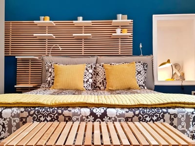 Chambre confortable au Borgo Guesthouse, avec un lit aux coussins colorés et un mur en bois moderne. Ambiance chaleureuse.