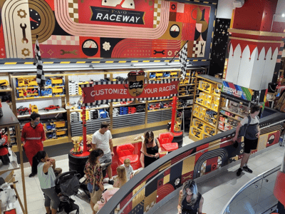 Race zone at FAO Schwarz, with colorful decorations and families having fun around customizable miniature cars.