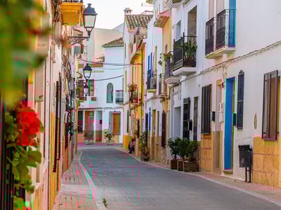 Picturesque street in La Nucia, adorned with white and colorful houses, evoking Mediterranean charm.
