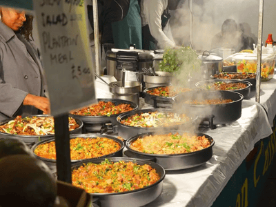 Delicious steaming spicy dishes served in pots at the Upmarket Brick Lane Food Hall, reflecting culinary diversity.