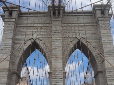 View of the iconic arches of the Brooklyn Bridge, illustrating the historic architecture and suspension cables.