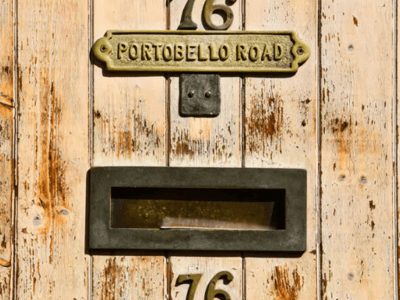 Number 76 on Portobello Road, a vintage metal plaque on a worn wooden wall, evoking London charm.