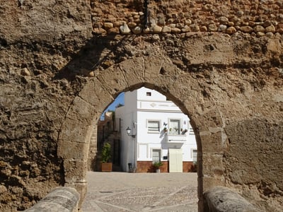 Vue d'un vieux pont en pierre à Buñol, menant à une place avec des bâtiments blanchis à la chaux, reflet de l'architecture historique.