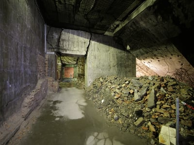 Tunnel sombre à Berliner Unterwelt, avec des débris et des murs en béton, évoquant l'histoire cachée de la ville.