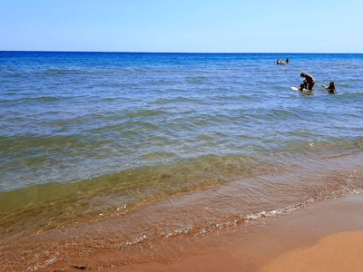 Plage tranquille à Castellaneta Marina, avec des baigneurs profitant des eaux cristallines sous un ciel bleu dégagé.