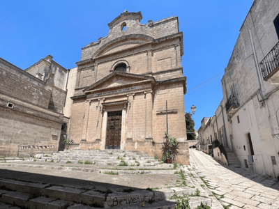Stone church at Porta degli Ebrei, with a blue sky, highlighting the historical architecture of the region.
