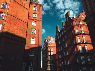 Victorian architecture in Kensington, with red brick buildings under a blue sky dotted with clouds.