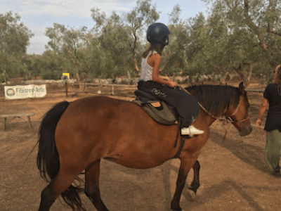 Une jeune cavalière monté sur un cheval, profitant d'une balade paisible dans la nature autour de la Masseria Fossa.
