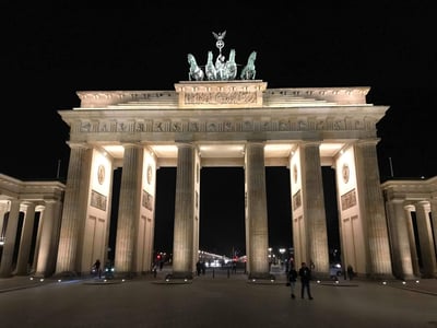 The Brandenburg Gate illuminated at night, an iconic emblem of Berlin, attracting visitors with its majesty.