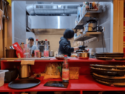 Cuisine coréenne en préparation chez Han BBQ, avec des chefs en action et une cuisine bien équipée.