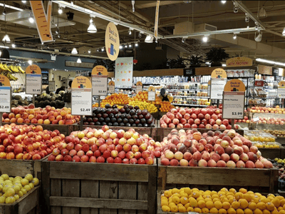 Colored rays of fresh fruits in Whole Foods Market, with prices indicated for apples and peaches.