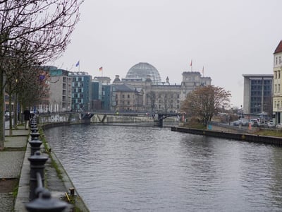 View of the Reichstag in Berlin with the glass dome, along the Spree, surrounded by trees in autumn.