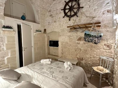 Comfortable room at La Chicca di Ostuni, with stone walls, maritime decor, and a cozy bed. Perfect for a getaway.