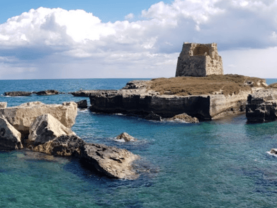 Ruines de la tour historique sur la côte de San Foca, entourées par les eaux turquoise de la Méditerranée.