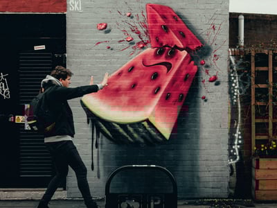A colorful watermelon mural in Shoreditch, with a passerby engaging with the dynamic and vibrant street art.