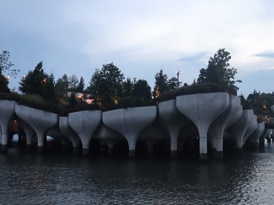 Concrete pillars supporting Little Island Park, illuminated at dusk, offering a unique view of the city.