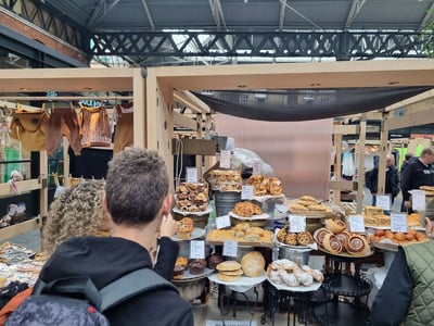 Une sélection de pâtisseries artisanales à Spitalfields Market, avec des visiteurs explorant les étals gourmands.