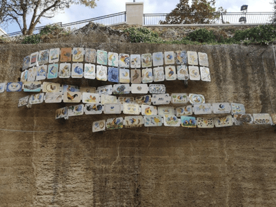 Des plaques en céramique décoratives accrochées à une paroi rocheuse dans le Quartier de la céramique.