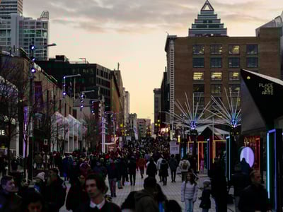 Animated view of the Quartier des Spectacles in Montreal, where crowds are enjoying an event at dusk.