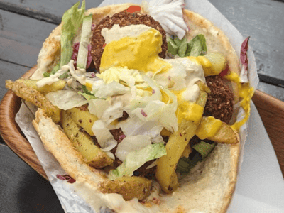 Falafel garni de légumes frais et sauce, servi dans un pita croustillant à Urban Falafel, une option végétale savoureuse.