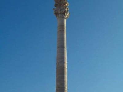 Colonne majestueuse de Lecce, symbole de l'architecture baroque, se dresse contre un ciel bleu éclatant.