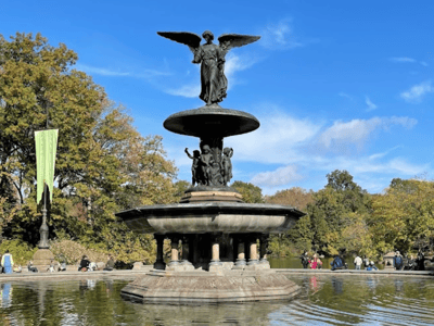 Bethesda Fountain in Central Park, adorned with a statue of an angel, surrounded by soothing autumn greenery.