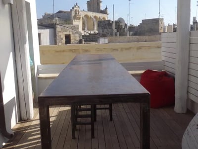 Sunny terrace of the Sui Tetti Hotel with a wooden table and a view of the city's historic buildings.