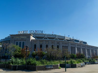Stade des Yankees sous un ciel bleu, entouré de verdure, emblème du baseball à New York et site d'événements sportifs emblématiques.