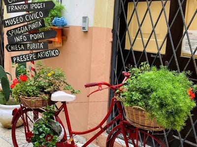 Bicycles decorated with plants, marking a picturesque street in Gallipoli, with signage for local attractions.