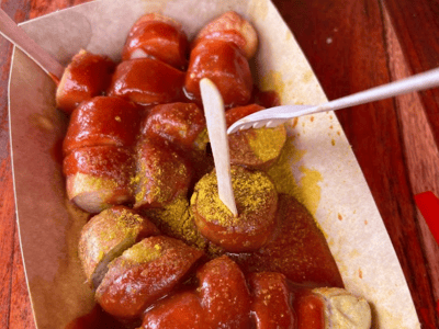 Sausage with curry sauce, ketchup, and pieces of fried potatoes, specialty of Curry 61 in Berlin.