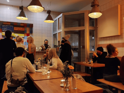 Ambiance chaleureuse à Salami Social Club, où les clients se retrouvent autour de tables en bois, profitant de l'atmosphère conviviale.