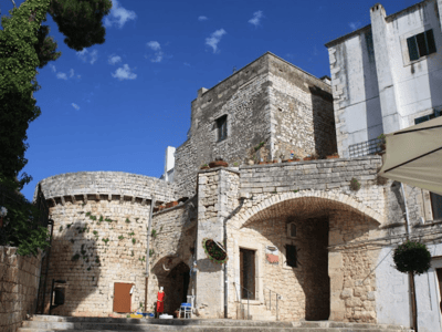 Architecture médiévale de Conversano, mettant en valeur des pierres anciennes et un ciel bleu éclatant.