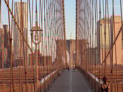 Brooklyn Bridge at dusk, with pedestrians and skyscrapers in the background, illustrating urban beauty.
