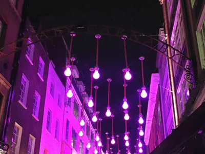 Lumières violettes illuminent Carnival Street la nuit, créant une ambiance festive dans ce célèbre quartier londonien.