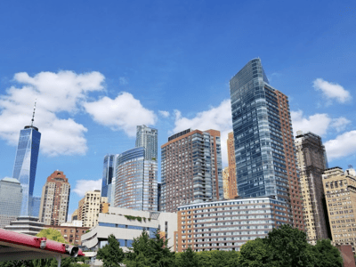 Modern skyscrapers in Midtown Manhattan, under a blue sky with some clouds, illustrating New York's dynamic architecture.