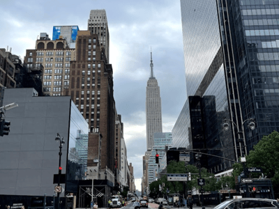View from West 34th Street, showing the Empire State Building framed by modern skyscrapers and busy traffic.