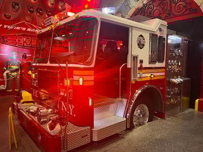 Camion de pompier emblématique au FDNY Fire Zone, illuminé et prêt à l'action, symbolisant le courage des premiers intervenants.